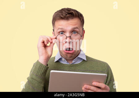 Mann mit Brille im grünen Pullover mit Tablet Computer gekleidet Stockfoto