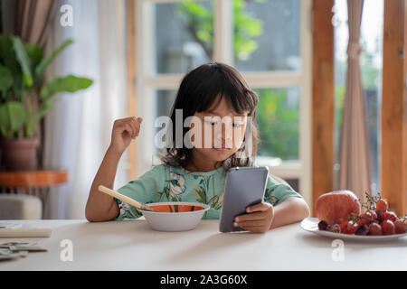 Kid mit Handy beim Frühstück auf den Tisch abgelenkt Stockfoto