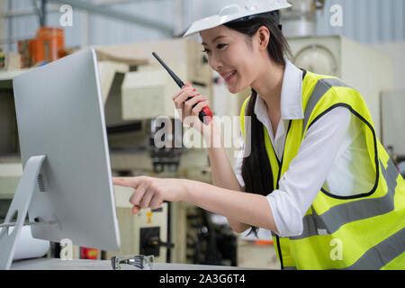 Asiatische Frau Ingenieur in einer Fabrik im Gespräch durch ein Radio. Stockfoto