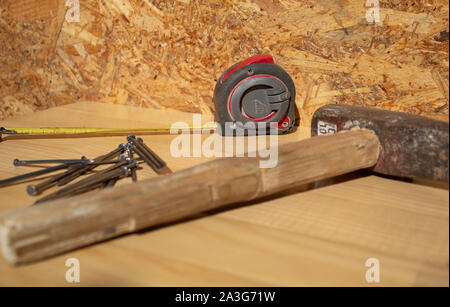 Hammer, Nägel und Maßband auf hölzernen Tisch Stockfoto