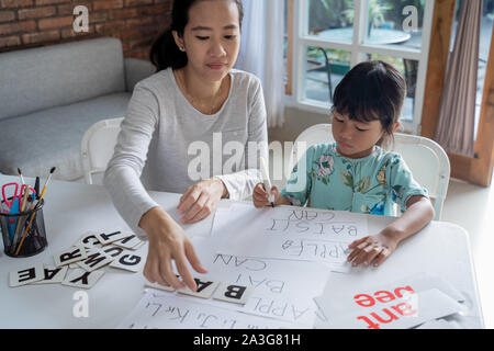 Mutter und Tochter das Lernen von Lesen und Schreiben zu Hause schreiben zusammen. homeschooling Aktivität Stockfoto