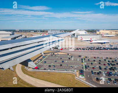 Blick vom Flugzeugfenster über den Parkplatz und die Hangars beim Anflug zum Flughafen Heathrow, London, England, Großbritannien Stockfoto