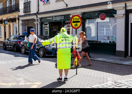 England, Berkshire, Eton, Eton High Street, Lollipop Lady Holding Stoppschild mit Fußgänger die Straße überqueren Stockfoto