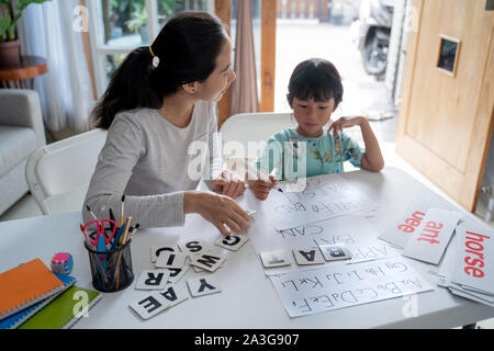 Mutter und Tochter das Lernen von Lesen und Schreiben zu Hause schreiben zusammen. homeschooling Aktivität Stockfoto