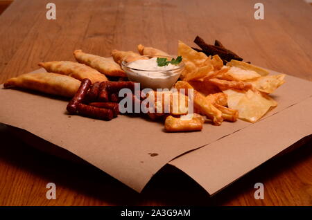 Tortilla Chips garniert mit Hackfleisch, Käse, Paprika und Koriander Blätter in der Platte auf hölzernen Tisch. Stockfoto