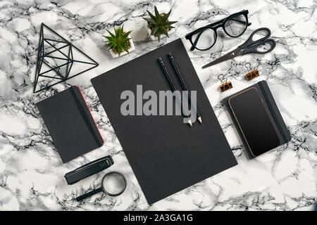 Blatt schwarzes Papier, Bleistifte, Gläser, Smartphone, Lupe, Schere, Hefter, zwei Ordner, Bügeleisen Dreieck Abbildung, grüne Pflanzen in den Töpfen und gold Stockfoto