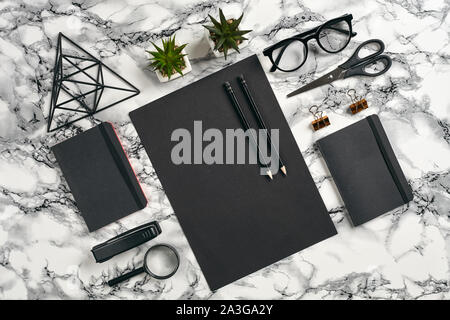 Blatt schwarzes Papier, Bleistifte, Brille, Lupe, Schere, Hefter, Ordner, Bügeleisen Dreieck Abbildung, grüne Pflanzen in den Töpfen und goldenen Büroklammern o Stockfoto