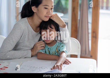 Porträt der jungen Mutter tröstet weinende Tochter zu Hause Stockfoto