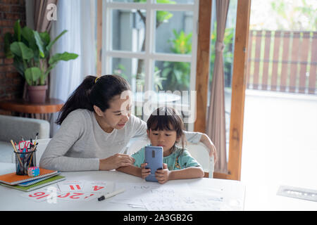 Mutter und Tochter studierte Trog Handy gerät zu Hause Stockfoto