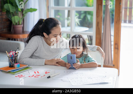 Elearning von Mutter ihre Tochter von Smartphone während homeschooling Aktivität zu Hause Stockfoto