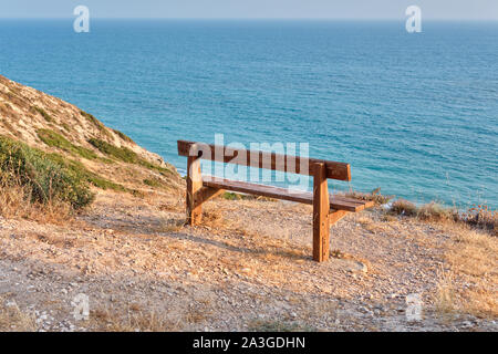 Nahaufnahme eines alten Holzbank stand auf einem Berg am Strand von azurblauem Meer und umgeben von einem herrlichen Natur Zyperns. Zu Stockfoto
