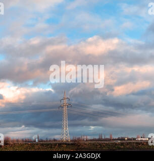 Hohe Spannung Pole an bewölkten Himmel Hintergrund. Industrielle Landschaft. Stockfoto