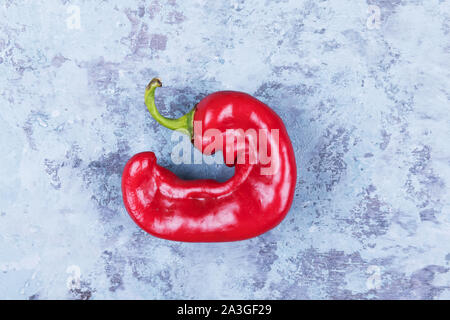 Eine trendige hässlichen roten Chili Pfeffer auf einem blauen grunge Hintergrund, Minimal Style, kreative Essen Konzept Stockfoto