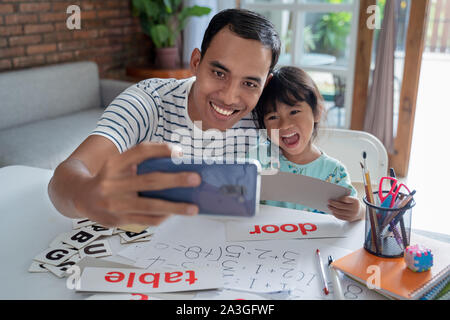 Vater und Tochter nehmen selfie zusammen mit Smartphone während des Studiums Stockfoto