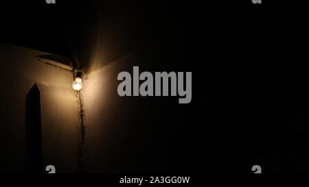 Glühlampe leuchtet in der Ecke der Mauer ist ein altes Haus beleuchtet die Straßen mit Gelb oder Orange Stockfoto