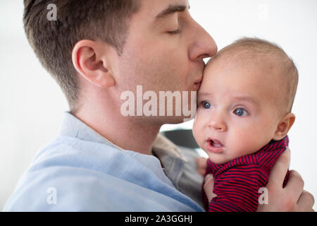 Liebevolle Vater 9 Monate alten Baby Sohn einen Kuss Stockfoto