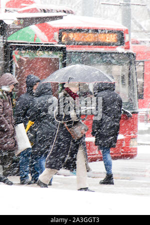 Belgrad, Serbien - Januar 3, 2019: Die Menschen warten auf öffentliche Verkehrsmittel Bushaltestelle an einem verschneiten Wintertag und eine elegante junge Frau unter Wandern Stockfoto