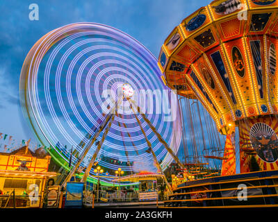 Riesenrad und Karussell am Abend auf der Messe Stockfoto