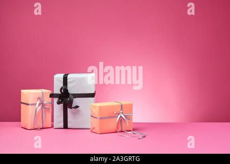 Verschiedene Größen, bunt gestreift und Normalpapier Geschenkboxen mit Bändern und Schleifen auf einem rosa Oberfläche und Hintergrund gebunden. Close-up, kopieren. Stockfoto