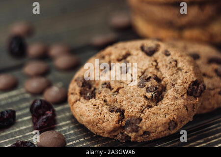 Ein Stapel von haferflocken Kekse mit Schokolade und kandierten Früchten liegt auf einem Holztisch. Rustikale Tabelle. Vintage Muskelaufbau. Diätetische nützliche Cookies Stockfoto