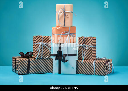 Verschiedene Größen, bunt gestreift und Normalpapier Geschenkboxen mit Bänder und Bögen auf blauem Untergrund und Hintergrund gebunden. Close-up, kopieren. Stockfoto