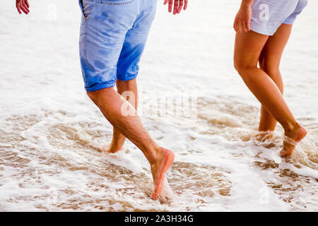 Paar Liebhaber auf dem Meer Schaum am Strand bei Sonnenuntergang. Füße hautnah. Stockfoto