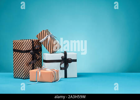 Verschiedene Größen, bunt gestreift und Normalpapier Geschenkboxen mit Bänder und Bögen auf blauem Untergrund und Hintergrund gebunden. Close-up, kopieren. Stockfoto