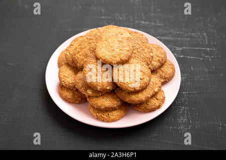 Cornflakes Cookies auf ein rosa Platte auf eine schwarze Fläche, Seitenansicht. Nahaufnahme. Stockfoto