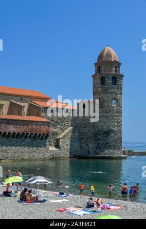 Frankreich, Pyrenees Orientales, Collioure, Urlauber unter den Sonnenschirmen auf boramar Strand mit Unserer Lieben Frau von den Engeln Kirche aus dem 17. Jahrhundert im Hintergrund Stockfoto