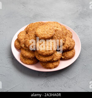 Cornflakes Cookies auf ein rosa Platte auf einen konkreten Hintergrund, Seitenansicht. Stockfoto