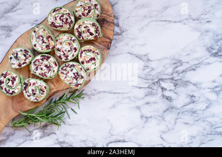 Frische hausgemachte Cranberry pinwheels mit Frischkäse, getrocknete Cranberries, Walnüsse, Ziegenkäse und Rosmarin für die Feiertage bereit. Ansicht von oben. Stockfoto