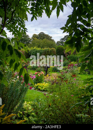 Chenies Manor versunkenen Garten Dahlie Zeit, durch eine glyzinie Schlüsselloch eingerahmt. Die zierteich Funktionen in der versunkenen Garten mit der Skulptur. Stockfoto