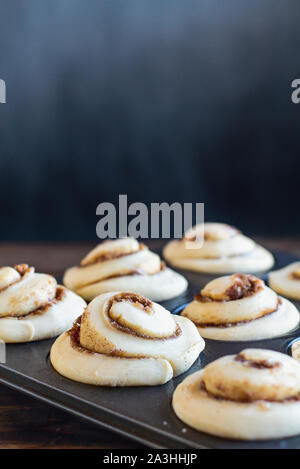 Frischen hausgemachten hohen Cinnamon Roll steigt in einem Muffin tin. Extreme selektiven Fokus mit unscharfen Vordergrund und Hintergrund. Stockfoto