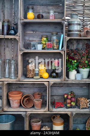 Altmodische, mit Früchten und Nüssen infundierte Gin-Gläser mit Vasen aus geschnittenen Blumen in einer Holzkiste. VEREINIGTES KÖNIGREICH Stockfoto