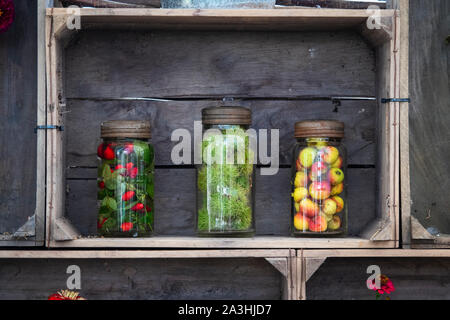 Altmodische Gin-Gläser für Kilner, die mit geernteten Früchten und Nüssen in einer Holzkiste, Großbritannien, infundiert sind Stockfoto