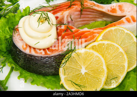 Fisch Lachs mit Zitrone und Soße liegt auf Kopfsalat Stockfoto