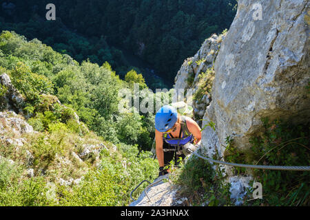 Frau auf Klettersteig Vadu Crisului, Rumänien, auf einer Felswand namens Peretele Zanelor, oben Crisul Repede Flusses, an einem warmen sonnigen Tag. Kopieren auf Stockfoto