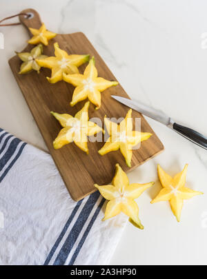 Scheiben von Star Fruit, Karambolen, auf Holz Schneidebrett angeordnet. Stockfoto