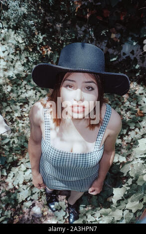 Latin Frau mit Hut und karierten kleid mit Kamera in den Wald. Stockfoto