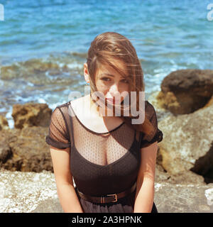 Junge Frau vor dem Meer kniet. Stockfoto