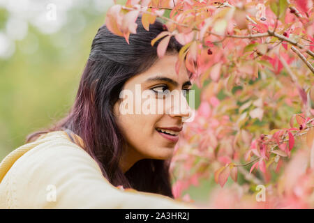 Junge Frau draußen vor der roten Blätter Stockfoto