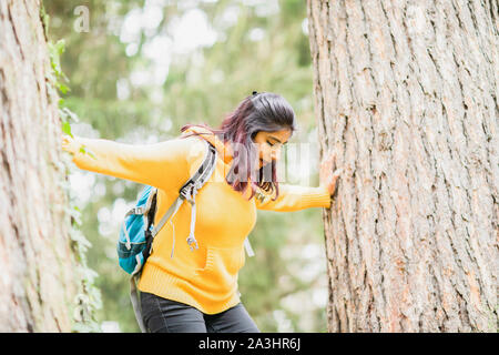 Junge Frau klettern in einem Baum mit Rucksack Stockfoto