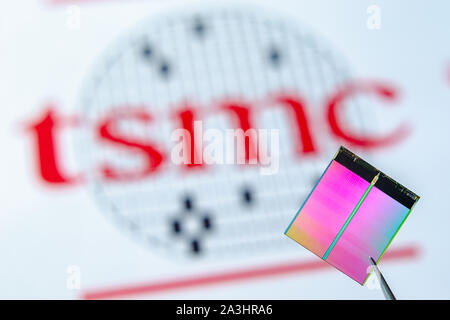 Nahaufnahme Foto von Microchip (aka Semiconductor Chip, Halbleiter, Integrierte Schaltkreise) Pinzette mit TSMC Logo auf einem Hintergrund. Stockfoto
