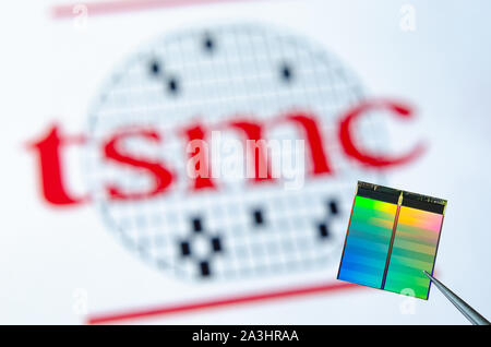 Nahaufnahme Foto von Microchip (aka Semiconductor Chip, Halbleiter, Integrierte Schaltkreise) Pinzette mit TSMC Logo auf einem Hintergrund. Stockfoto