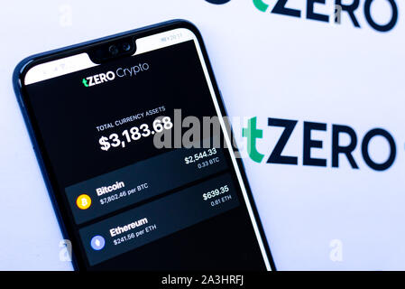 TZero Logos auf die Broschüre und das Smartphone mit dem tZERO Crypto App Screenshot. Stockfoto