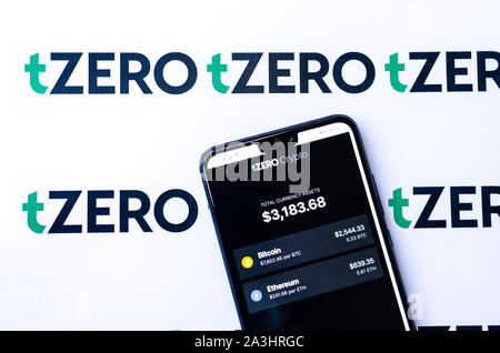 TZero Logos auf die Broschüre und das Smartphone mit dem tZERO Crypto App Screenshot. Stockfoto