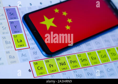 Das Foto von China Flagge auf Huawei smartphone, das auf dem Periodensystem um die Gruppen der Seltenen Erden. Konzept für einen Handelskrieg. Stockfoto