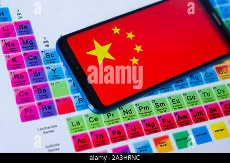 Das Foto von China Flagge auf Huawei smartphone, das auf dem Periodensystem um die Gruppen der Seltenen Erden. Konzept für einen Handelskrieg. Stockfoto