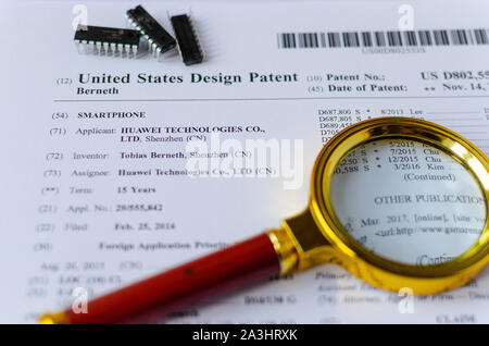 Die Nahaufnahme Foto von HUAWEI US-Patent, Lupe und Mikrochips. Chinesische Technologien sind Gegenstand der Untersuchung. Stockfoto
