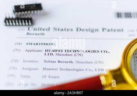 Die Nahaufnahme Foto von HUAWEI US-Patent, Lupe und Mikrochips. Chinesische Technologien sind Gegenstand der Untersuchung. Stockfoto
